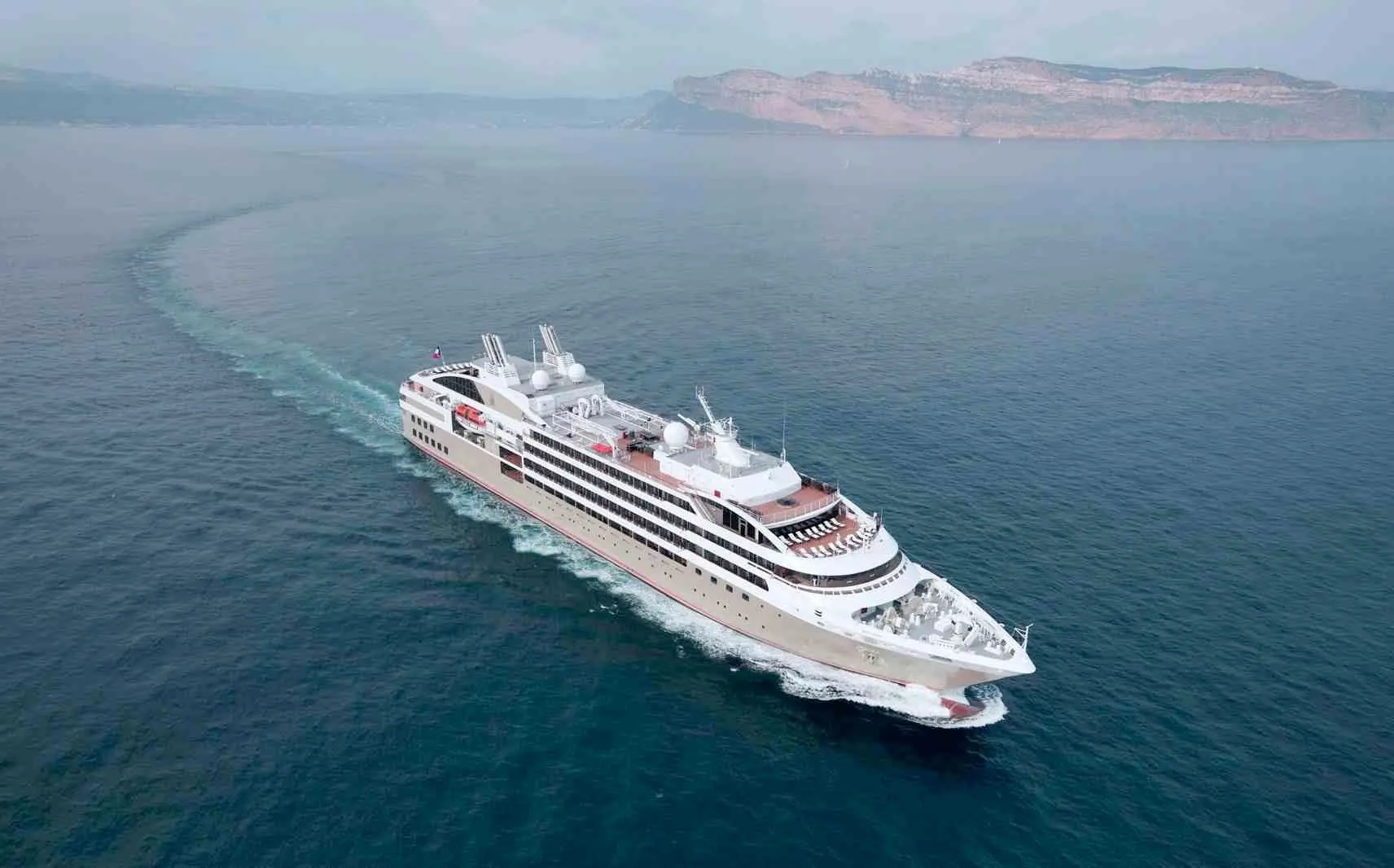 A Ponant expedition yacht cruising across a calm blue sea